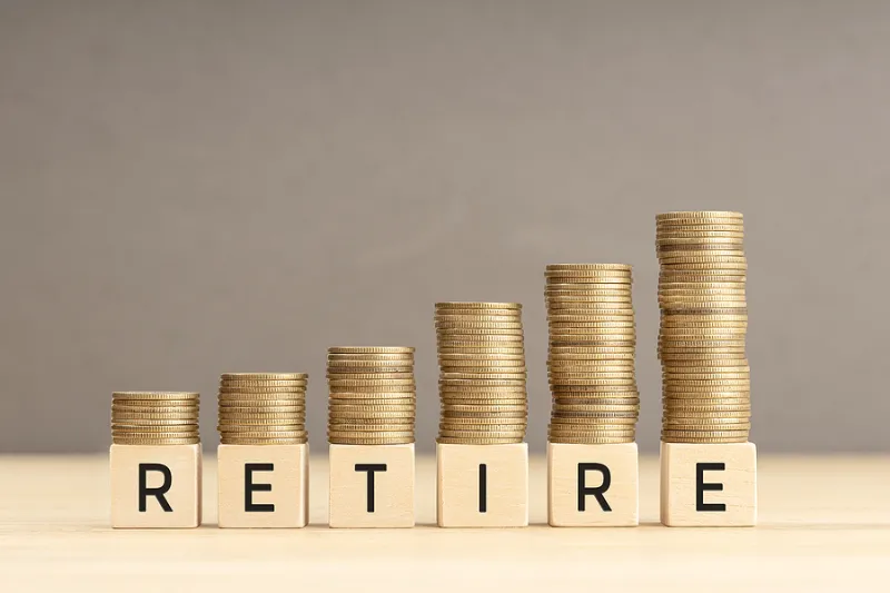 Retire Word In Wooden Blocks With Coins Stacked In Increasing St